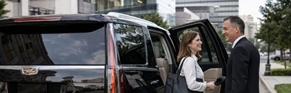 A client using an hourly hire chauffeur service, with the driver opening the car door for her.